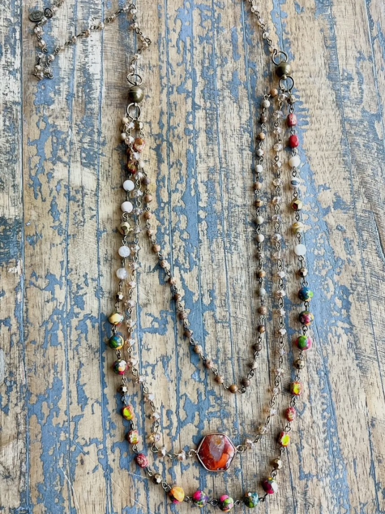 Earth & Embers Boho Gemstone Multi-chain Necklace Shown Long on Table with 3 Layers.