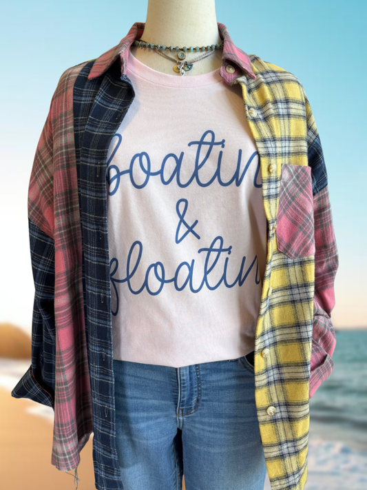 Boatin' & Floatin' tee shown on a form with our Free Spirit Plaid Flannel and 2 necklaces, with a lake background.