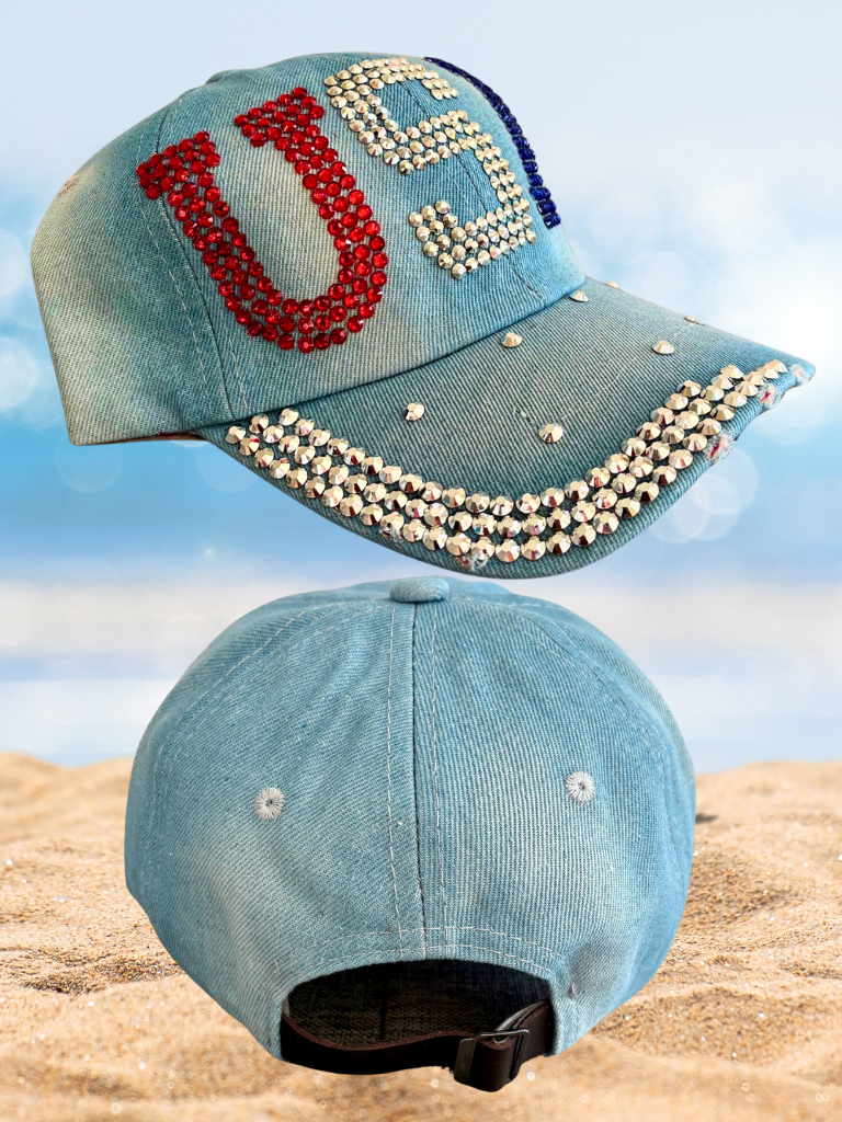 Blue denim cap with 'USA' lettering and rhinestone embellishments on a beach background