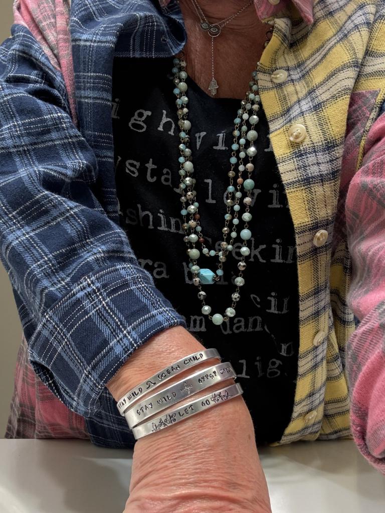 Close-up of a person wearing all 3 style bracelets and the Selena Necklace with our Free Spirit Plaid Flannel shirt over our Lover of Light tee.  