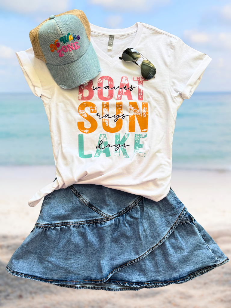 Boat Waves, Sun Rays, Lake Days V-neck tee with colorful text, denim No Wake Zone cap, and denim mini skirt on a beach.