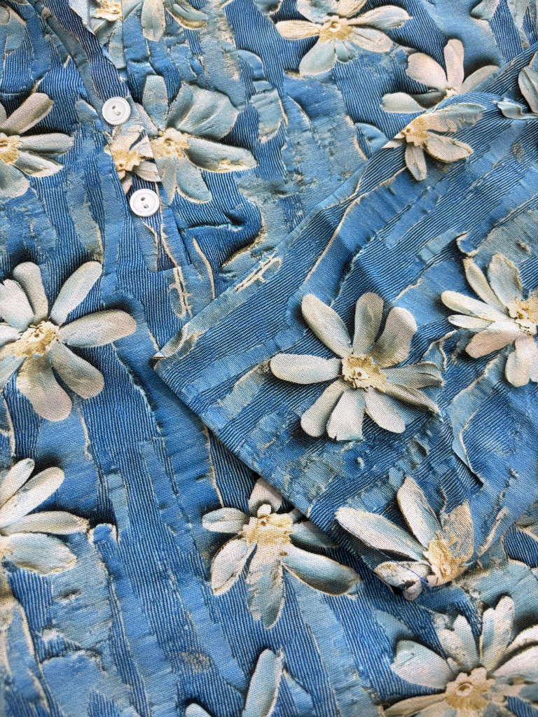 Close-up of a blue fabric with floral patterns and buttons.