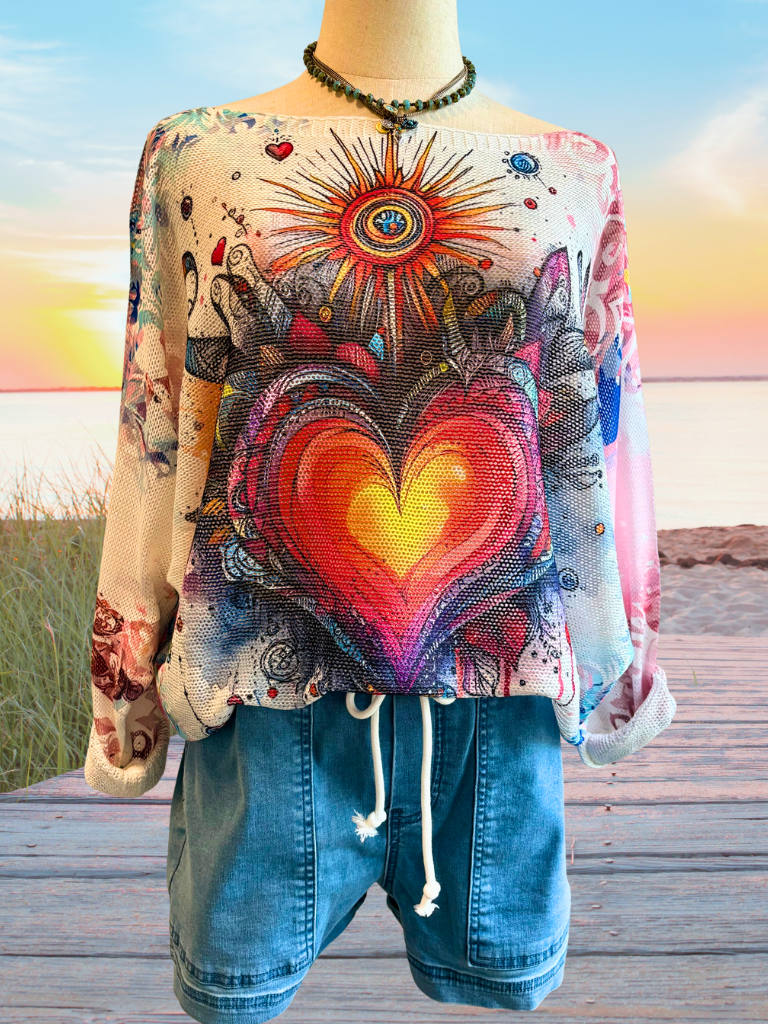 Hearts Aglow - Ladies Loose Knit, Round Neck, Boho Sweater Front View Shown with the Weekend Wanderer Boat Shorts. Bold, heart-and-sun inspired design with colorful accents