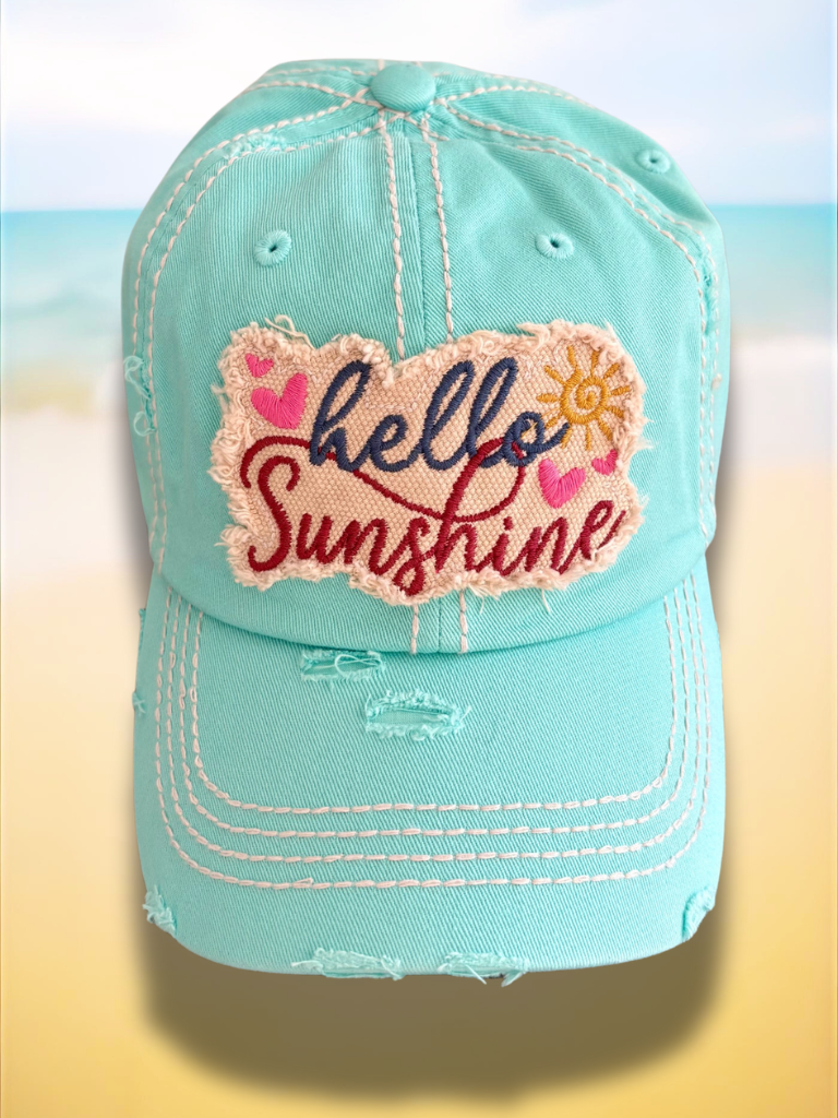 Turquoise cap with 'hello Sunshine' patch on a beach background