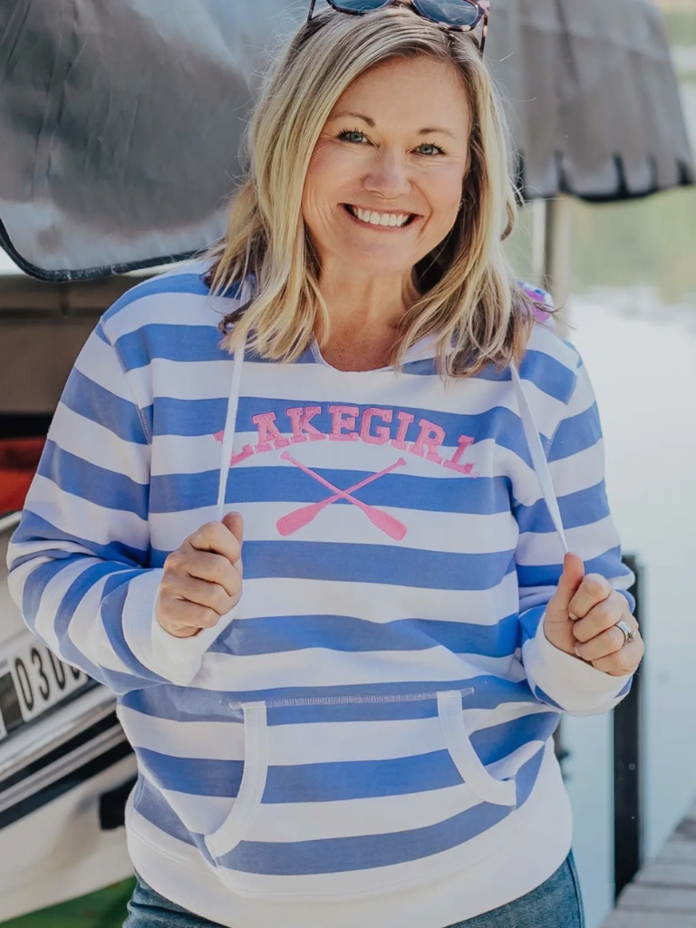 Woman wearing a blue and white striped hoodie with 'Lakegirl' text, standing in front of a boat.