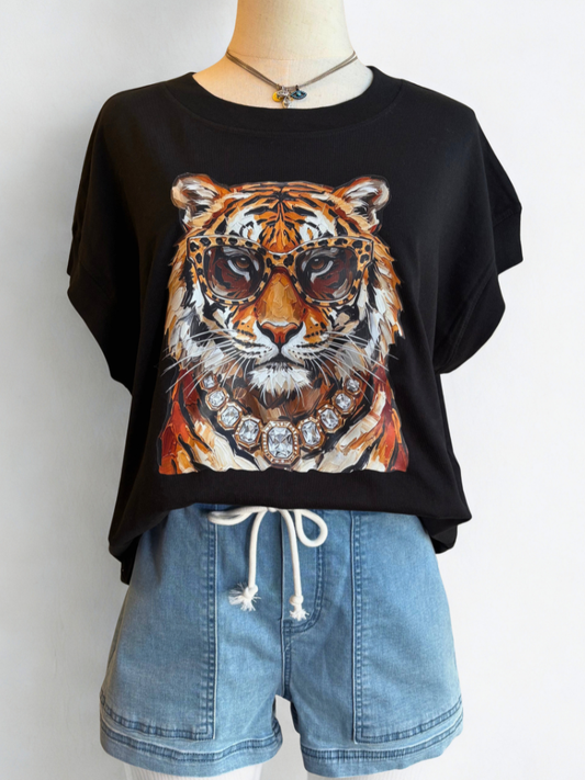 A black short-sleeve t-shirt with a large graphic print of a tiger wearing sunglasses and a jeweled collar, styled on a mannequin with blue denim shorts.